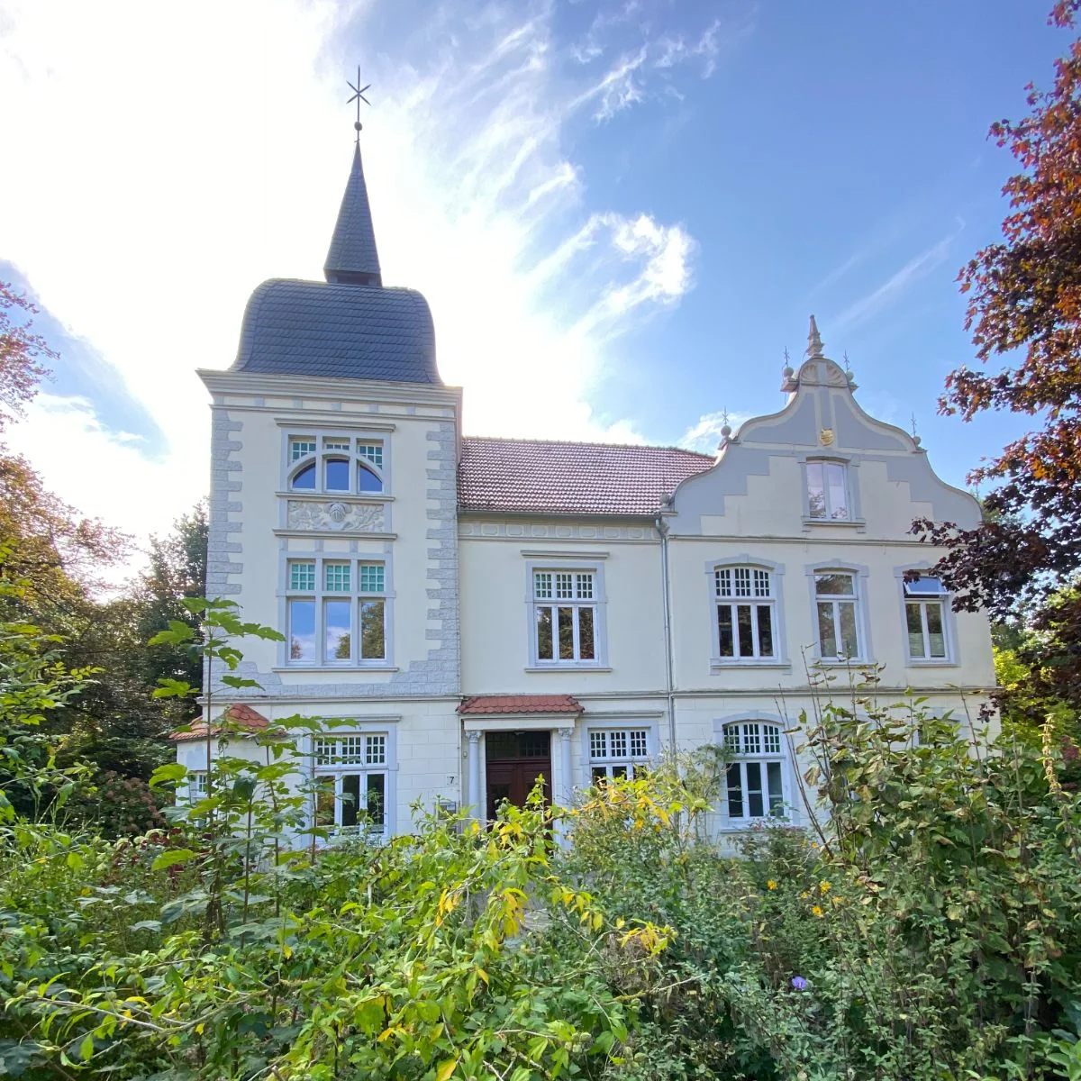 Das historische Gutshaus Hundsmühlen mit weißer Fassade und Turm